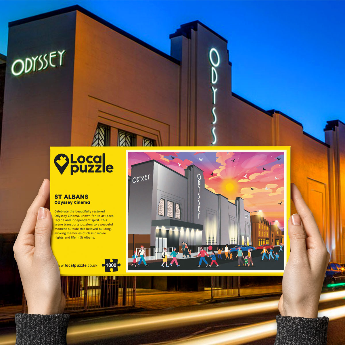 Person holding "local Puzzle" box for St Albans Odyssey Cinema jigsaw puzzle in front of the actual location