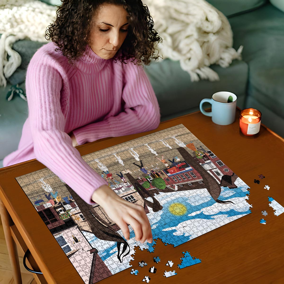 Woman in pink sweater working on our Letchworth Leys Square jigsaw puzzle on a wooden table with a cup and candles in the background