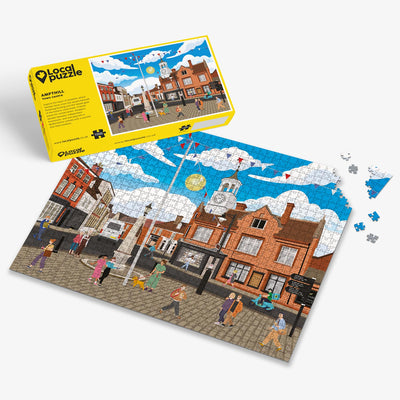 Ampthill Town Centre Jigsaw puzzle with a colourful scene of a town centre and yellow box packaging on a white background