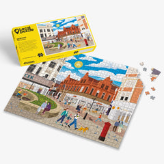 Bedford town centre Jigsaw puzzle with a colourful scene of a town square and yellow box packaging on a white background