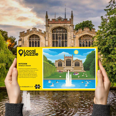 Person holding "local Puzzle" box for Hitchin St Mary's Church jigsaw puzzle in front of the actual location 
