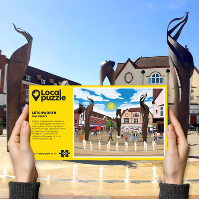 Person holding "local Puzzle" box for Letchworth Leys Square jigsaw puzzle in front of the actual location 