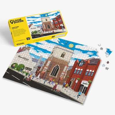 Shefford High Street Jigsaw puzzle with a colourful scene of a town centre and yellow box packaging on a white background
