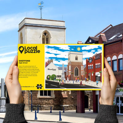 Hands holding "local Puzzle" box for Shefford High Street jigsaw puzzle in front of the actual location 