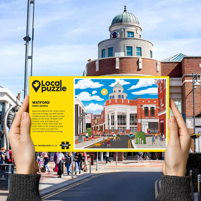 Person holding "local Puzzle" box for Watford Town Centre jigsaw puzzle in front of the actual location 