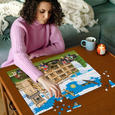 Woman in pink sweater working on a Biggleswade Shuttleworth House jigsaw puzzle on a wooden table with a cup and candles in the background