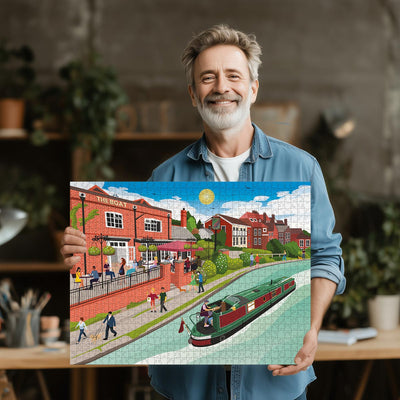 Man holding a completed Berkhamsted Grand Union Canal jigsaw puzzle of a canal scene with buildings and people.