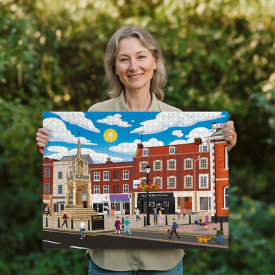 Woman holding a completed Leighton Buzzard Town Centre jigsaw puzzle in her garden