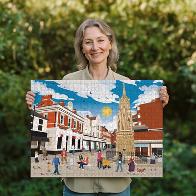 Woman holding a completed Waltham Cross town centre jigsaw puzzle in her garden