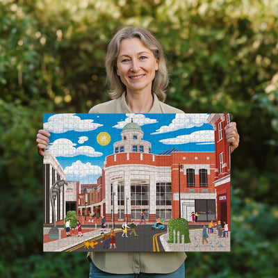 Woman holding a completed Watford town centre jigsaw puzzle in her garden