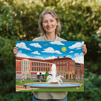 Woman holding a completed Welwyn Garden City Town Centre jigsaw puzzle in her garden